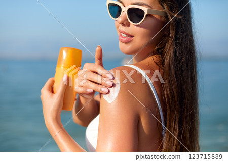 Enjoying Summer at the Beach While Applying Sun Cream for Skin Protection Enjoying Summer at the Beach While Applying Sun Cream for Skin Protection 123715889