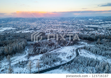 A serene winter evening unfolds above Liberec City, showcasing the enchanting snow-covered landscape with winding roads and vibrant pink hues in the sky. A serene winter evening unfolds above Liberec City, showcasing the enchanting snow-covered landscape with winding roads and vibrant pink hues in the sky. 123716187