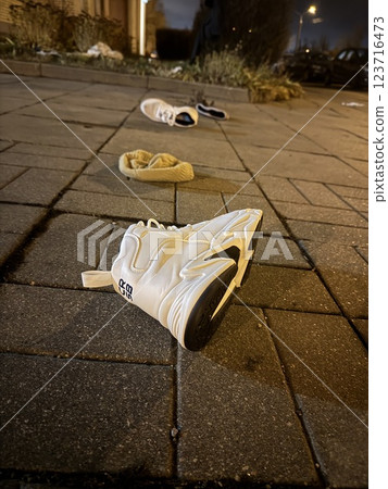 Abandoned white sneaker on urban sidewalk at night 123716473
