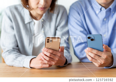 一對中年夫妻在家看智慧型手機 一對中年夫妻在家看智慧型手機 123716592