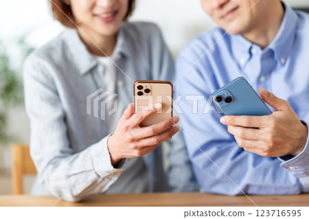 一對中年夫婦在家開心地看著智慧型手機 123716595
