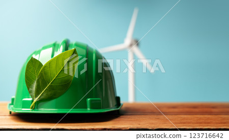 ESG and Clean Energy Concept. Hard Hat with Green Leaf. Wind Turbine Generator as background. Produce a Green Power. World Earth Day, Sustainable Resources, Environmental Care ESG and Clean Energy Concept. Hard Hat with Green Leaf. Wind Turbine Generator as background. Produce a Green Power. World Earth Day, Sustainable Resources, Environmental Care 123716642