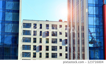 View of an modern apartment building standing next to a new modern office building with a glass facade. View of an modern apartment building standing next to a new modern office building with a glass facade. 123716804