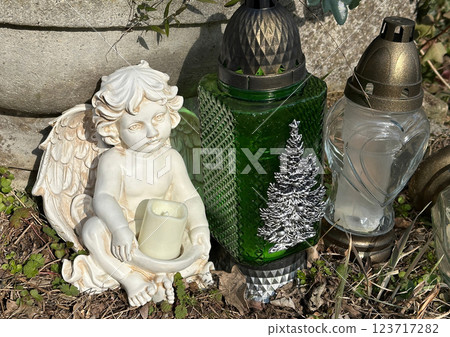 Angel figurine and lanterns on a tombstone in the public cemetery 123717282