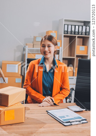 Fashion blogger concept, Young Asian women selling clothes on video streaming.Startup small business SME, using smartphone or tablet taking receive and checking in office 123720113