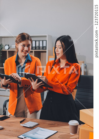 Fashion blogger concept, Young Asian women selling clothes on video streaming.Startup small business SME, using smartphone or tablet taking receive and checking in office 123720115