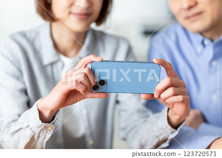 A middle-aged couple happily looking at a smartphone at home 123720571