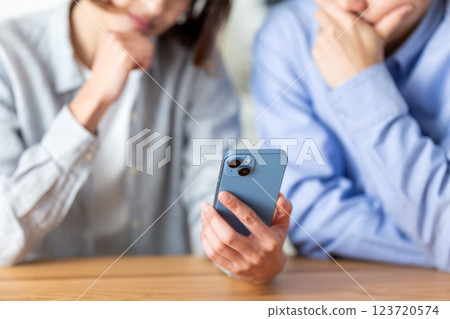 A middle-aged couple feeling depressed while looking at their smartphones at home 123720574