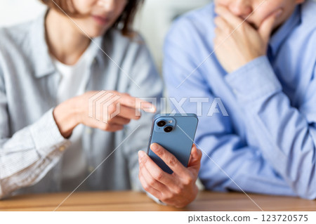 A middle-aged couple feeling depressed while looking at their smartphones at home 123720575