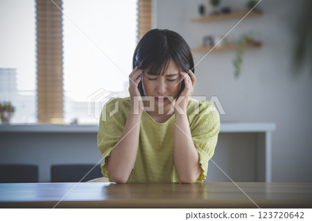 一名 30 多歲女性摀著太陽穴，低頭 123720642