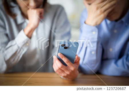 A middle-aged couple feeling depressed while looking at their smartphones at home 123720687