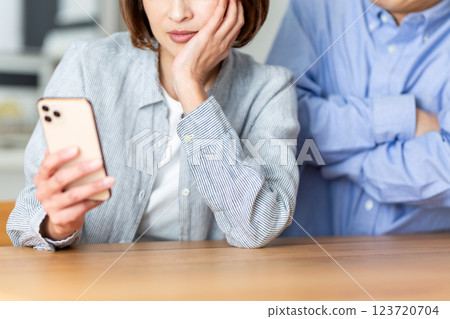 A husband scolds his wife for constantly looking at her smartphone (middle-aged couple) 123720704
