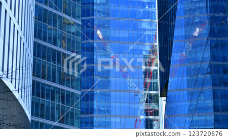 Glass building with transparent facade of the building and blue sky. Structural glass wall reflecting blue sky. Abstract modern architecture fragment. Contemporary architectural background. 123720876