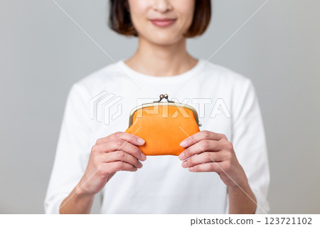 一名中年婦女拿著橘色錢包微笑 一名中年婦女拿著橘色錢包微笑 123721102