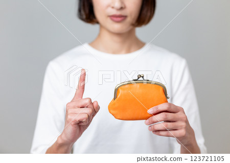A middle-aged woman holding an orange purse and pointing her index finger up A middle-aged woman holding an orange purse and pointing her index finger up 123721105