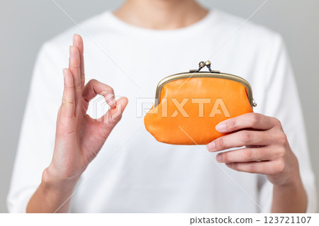 一名中年婦女拿著橘色錢包，比劃著圓圈 123721107