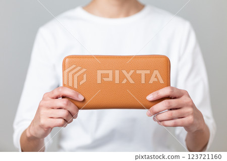 Middle-aged woman holding an orange long wallet 123721160