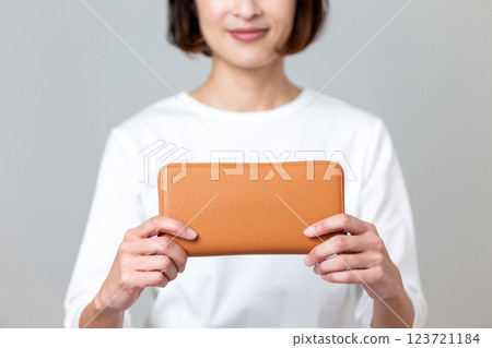 Middle-aged woman holding an orange long wallet Middle-aged woman holding an orange long wallet 123721184