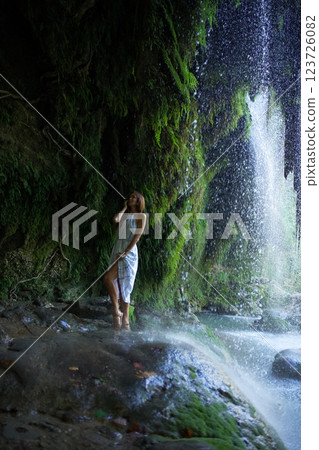 Woman Enjoying a Refreshing Waterfall in Lush Nature  123726082