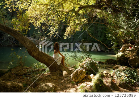 Woman Sitting on Tree by Waterfall Pool Woman Sitting on Tree by Waterfall Pool 123726089