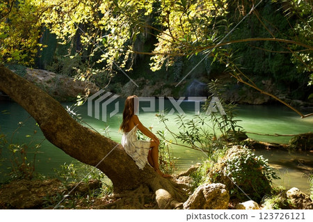Woman Sitting on Tree Overlooking Green Lagoon Woman Sitting on Tree Overlooking Green Lagoon 123726121