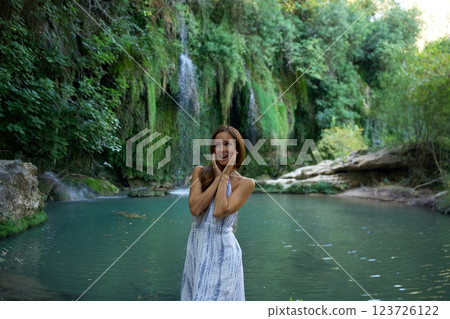 Excited Woman Enjoying Nature by a Waterfall and River  123726122