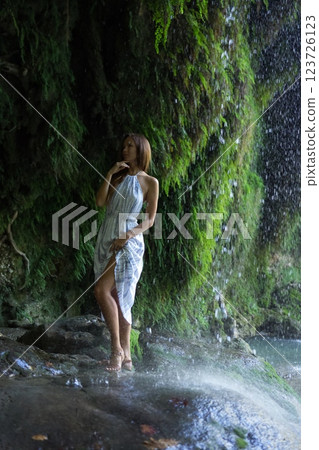 Woman Standing Gracefully Under a Misty Waterfall  123726123