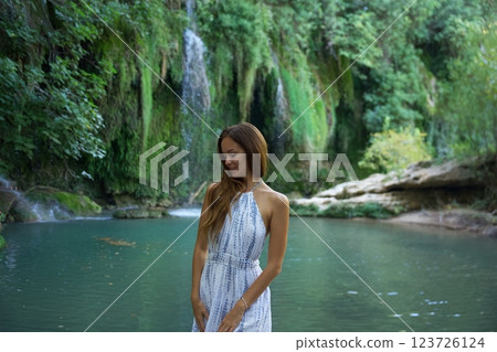 Woman in White Dress Relaxing by a Waterfall and River  123726124