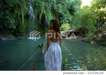 Woman in Elegant Dress Admiring Waterfall and River  123726126