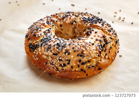 Bagel with sesame seeds, on baking paper Bagel with sesame seeds, on baking paper 123727073