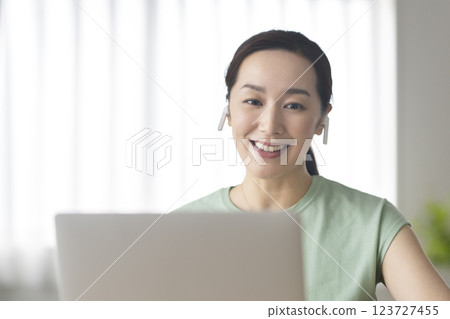 一名 30 多歲女性戴著耳機，面對筆記型電腦，視訊聊天，線上通話，圖像 123727455