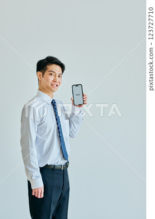 A young man in his 20s holding a smartphone NISA 123727710