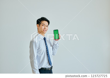 20 多歲的年輕人拿著智慧型手機 綠色背景 123727725