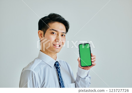 20 多歲的年輕人拿著智慧型手機 綠色背景 123727726