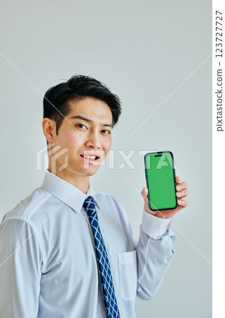 20 多歲的年輕人拿著智慧型手機 綠色背景 123727727