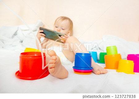 child in hospital lying in bed with mobile phone smiling 123727838