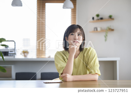 A woman in her 30s thinking with her chin in her hands 123727951