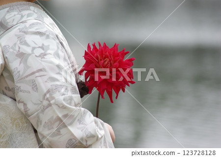 Woman in kimono holding red flower 123728128