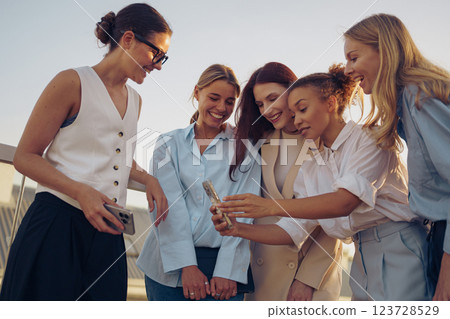 Joyful women share a delightful moment viewing photos in a vibrant setting, celebrating friendship Joyful women share a delightful moment viewing photos in a vibrant setting, celebrating friendship 123728529