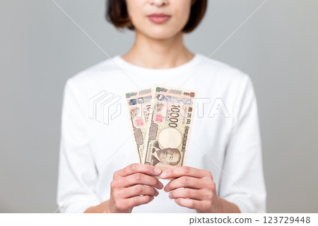 Middle-aged woman holding a 10,000 yen bill 123729448