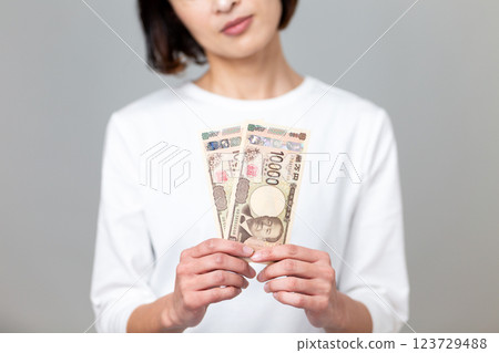 A middle-aged woman holding a 10,000 yen bill and worrying A middle-aged woman holding a 10,000 yen bill and worrying 123729488