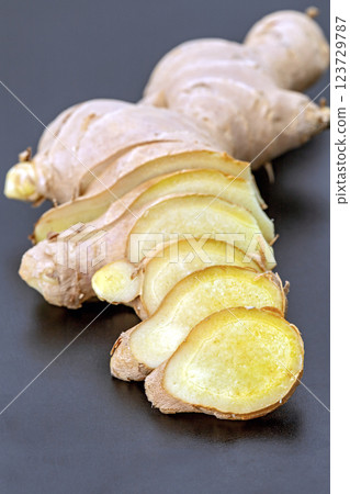 Ginger is cut into pieces and placed on a black plate ready for cooking. Ginger is cut into pieces and placed on a black plate ready for cooking. 123729787
