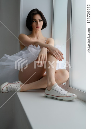 Ballet dancer in lingerie poses gracefully at a studio window 123729952