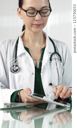 Female doctor in white coat using digital tablet in modern healthcare setting, interacting with patient data, vertical portrait. Medicine concept Female doctor in white coat using digital tablet in modern healthcare setting, interacting with patient data, vertical portrait. Medicine concept 123730033