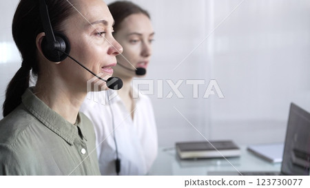 Focused female call center operator in green casual blouse is assisting clients online, providing customer support and answering inquiries. Call center Focused female call center operator in green casual blouse is assisting clients online, providing customer support and answering inquiries. Call center 123730077