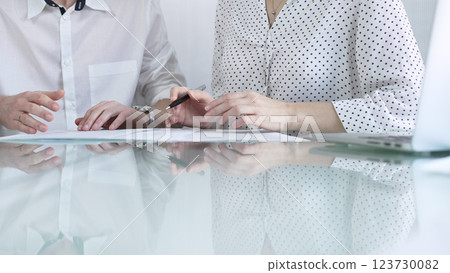 Business colleagues reviewing a contract, engaging in negotiations and strategic decision making in modern glass office, white casual dress style. Businesspeople concept 123730082