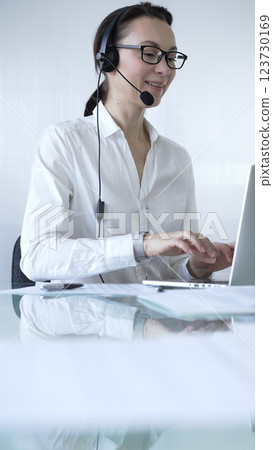 Female secretary wearing headset and working on laptop, providing customer support or online service. Business people concept Female secretary wearing headset and working on laptop, providing customer support or online service. Business people concept 123730169