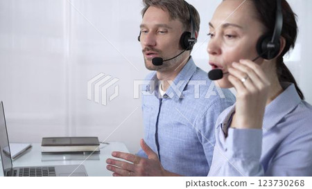 Focused female call center operator in blue casual blouse is assisting clients online, providing customer support and answering inquiries. Call center concept 123730268