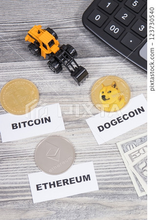 Cryptocurrency coins, dollar bills, miniature excavator and calculator 123730540