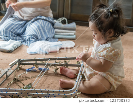 [Baby with twin tails touching a laundry hanger] 123730583